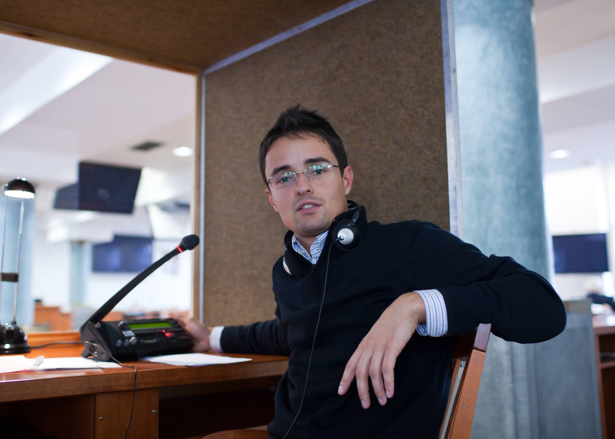 An interpreter in a sound booth conducting simultaneous interpreting services for courtroom proceedings.