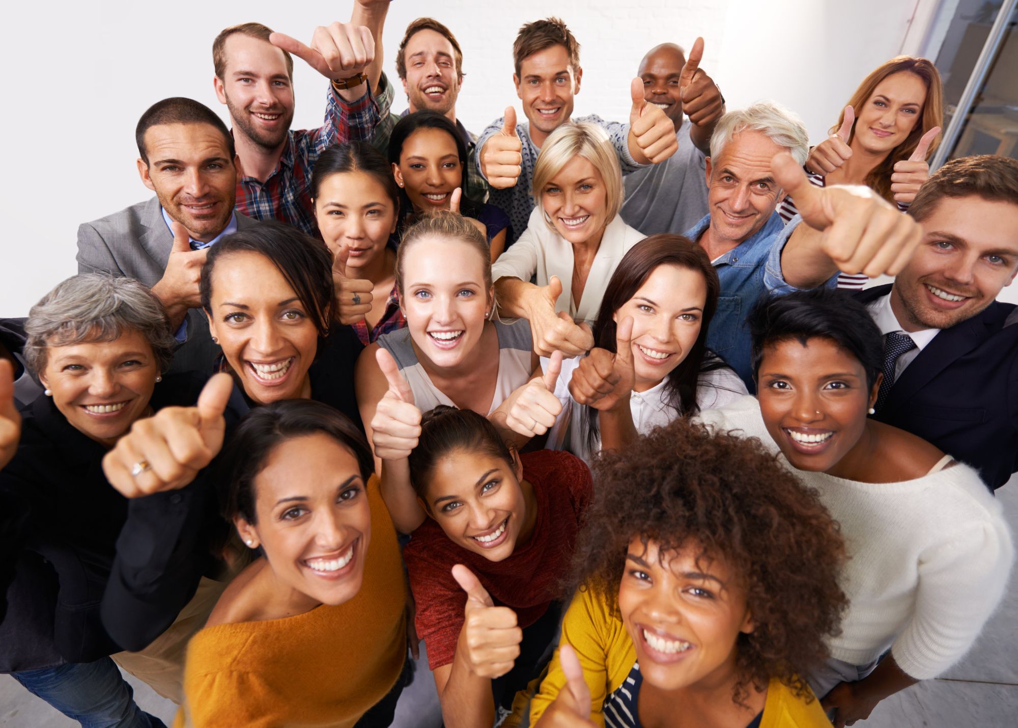 A group of diverse people smiling with thumbs up.